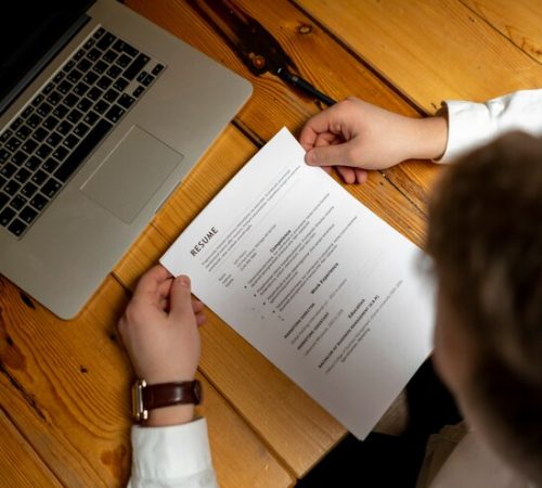 close-up-office-worker-hand-read-resume-wooden-surface_63762-79